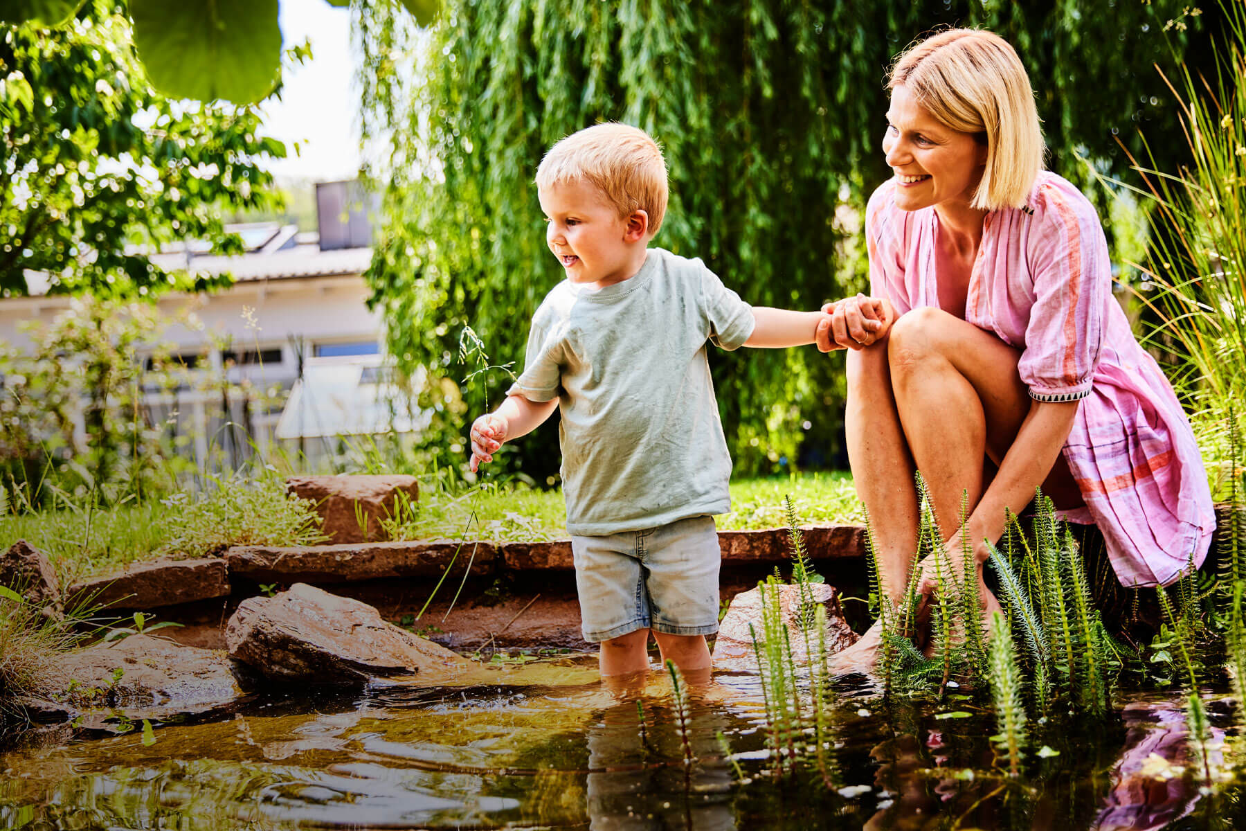 Bild einer Frau, die mit ihrem Kind im Wasser spielt.